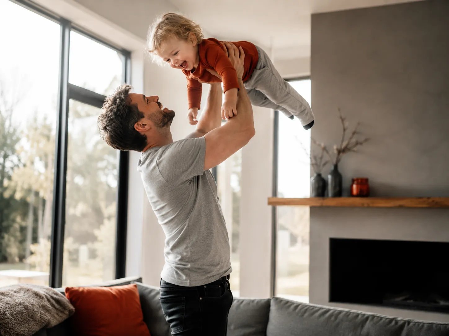 Father lifting his toddler in a bright room, fatherhood and fertility on TRT