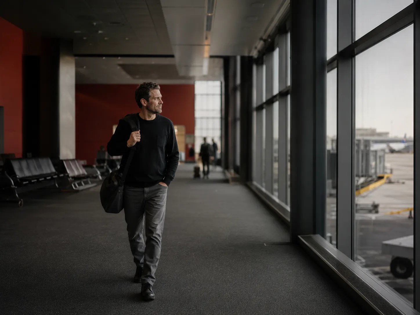 Man with a carry-on bag walking through an airport terminal before a flight